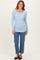 woman wearing a light blue long sleeve ribbed top with a scoop neckline and paired with high-waisted jeans