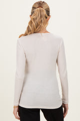 woman wearing a light beige long sleeve maternity top viewed from the back
