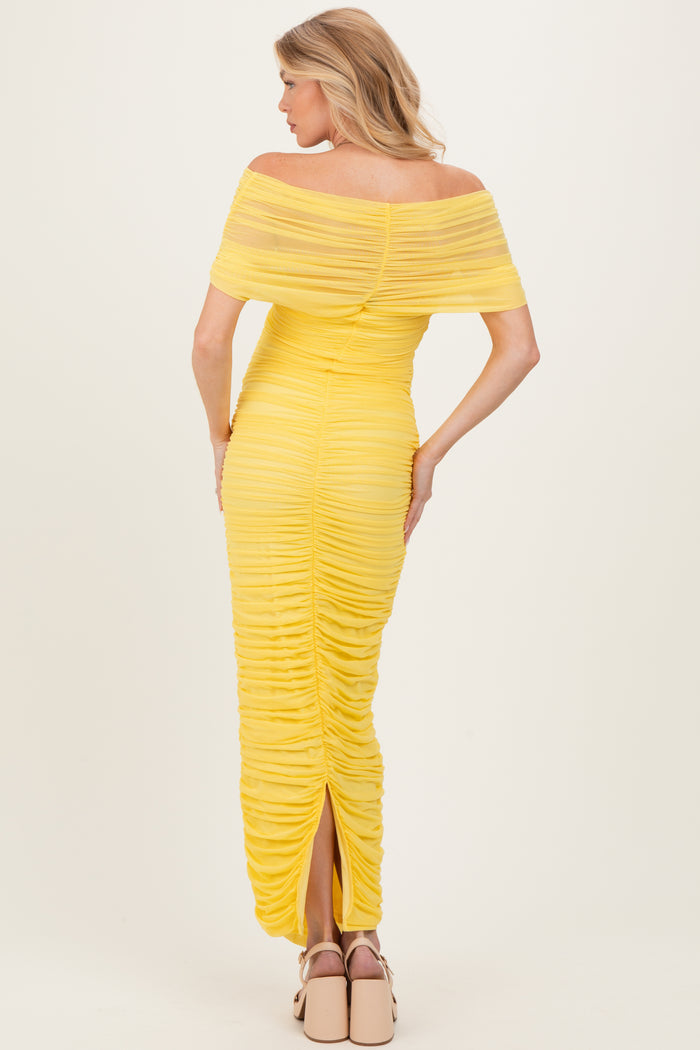 woman wearing a yellow off-shoulder maternity dress with ruched details and a split back