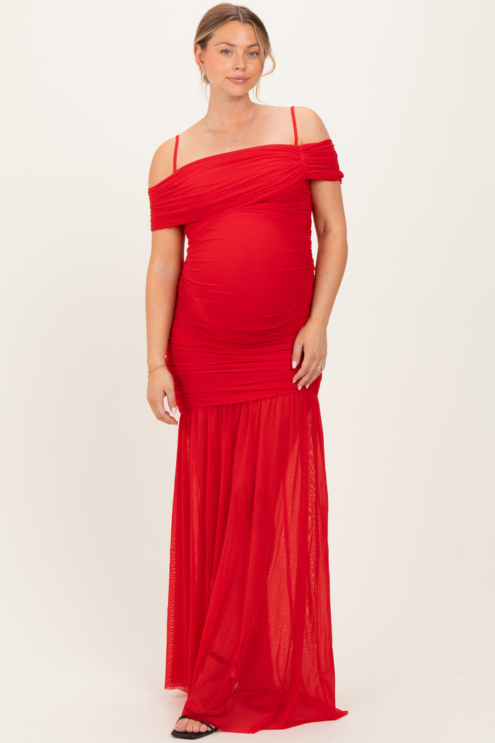 woman wearing a red off-the-shoulder maternity gown with ruching and a flowing skirt, showcasing her baby bump
