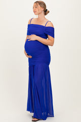 woman wearing a royal blue off-the-shoulder maternity gown with ruching and a flowing skirt, highlighting her baby bump