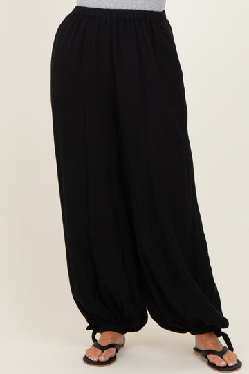 woman wearing black harem pants with a relaxed fit and elastic waistband, paired with black sandals