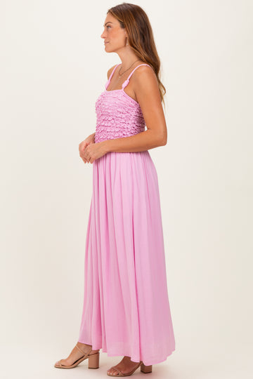 woman wearing a pink maxi dress with a textured bodice and flowing skirt, styled with sandals