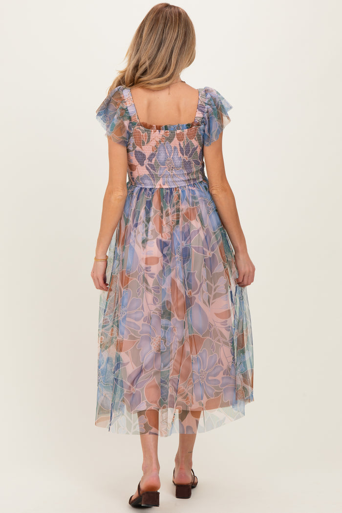 woman wearing a floral printed maternity dress with ruffled sleeves and a smocked bodice, showing a flowy tulle skirt from the back