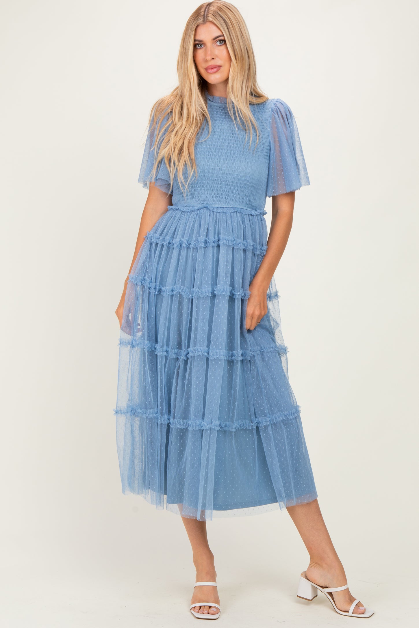 woman wearing a light blue tiered midi dress with puff sleeves and ruffled details, styled with white heels