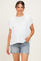 woman wearing a white maternity t-shirt and distressed denim shorts, smiling and posing with a relaxed fit