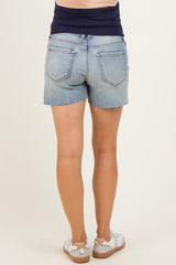 woman wearing light wash denim maternity shorts with frayed hem, showing the back view