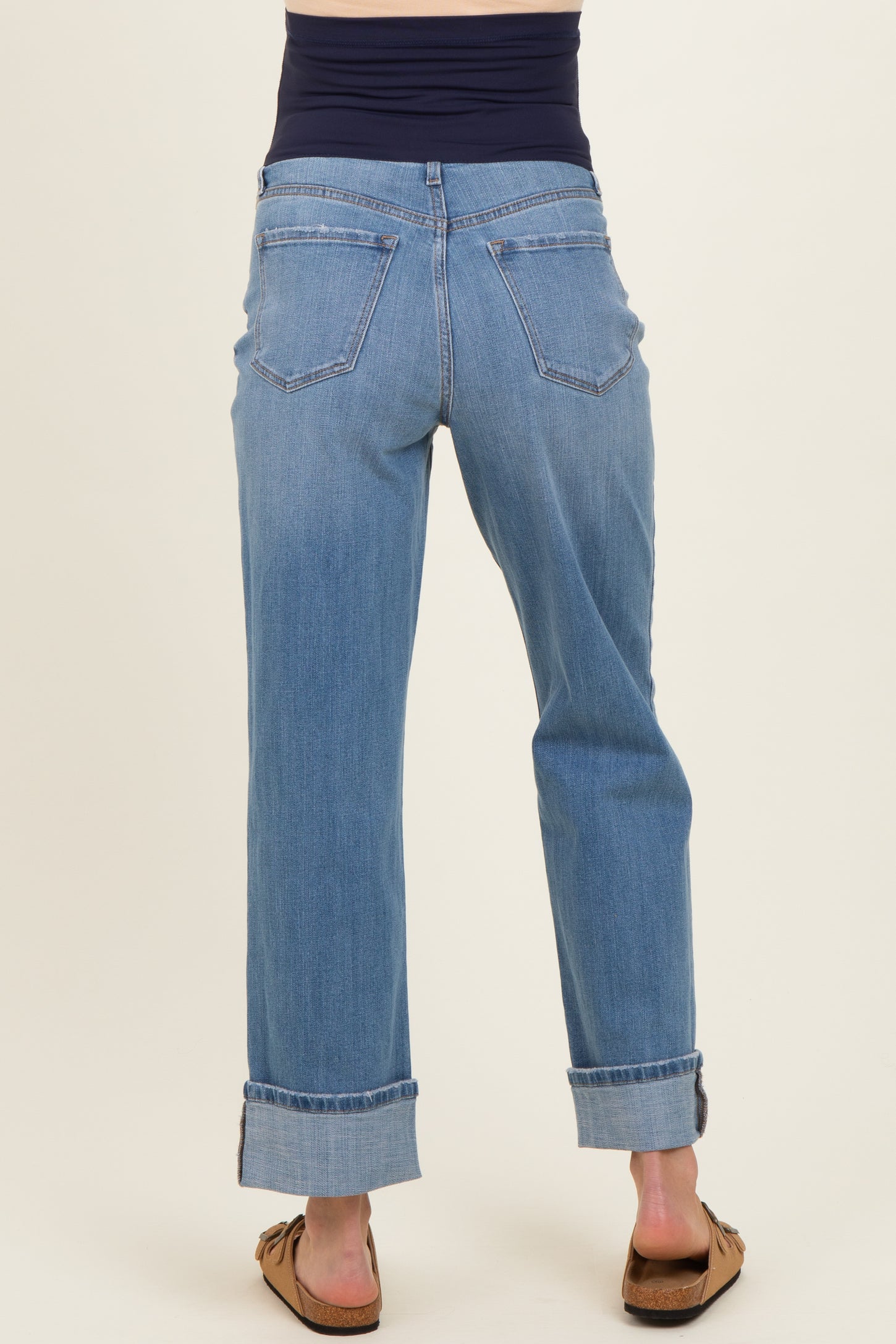 woman wearing light blue maternity jeans with a rolled cuff and a navy blue belly panel, viewed from the back