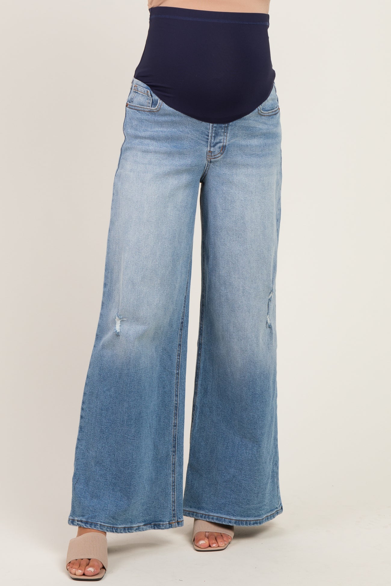 woman wearing light blue maternity wide-leg jeans with a dark blue over-the-bump waistband and distressed details