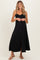 woman wearing a black maternity maxi dress with button details and adjustable straps, showing a baby bump