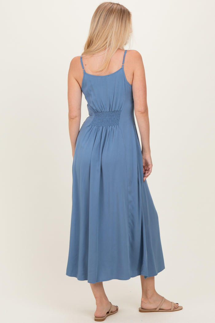 woman wearing a light blue sleeveless maxi dress with a smocked back detail and a flowing skirt