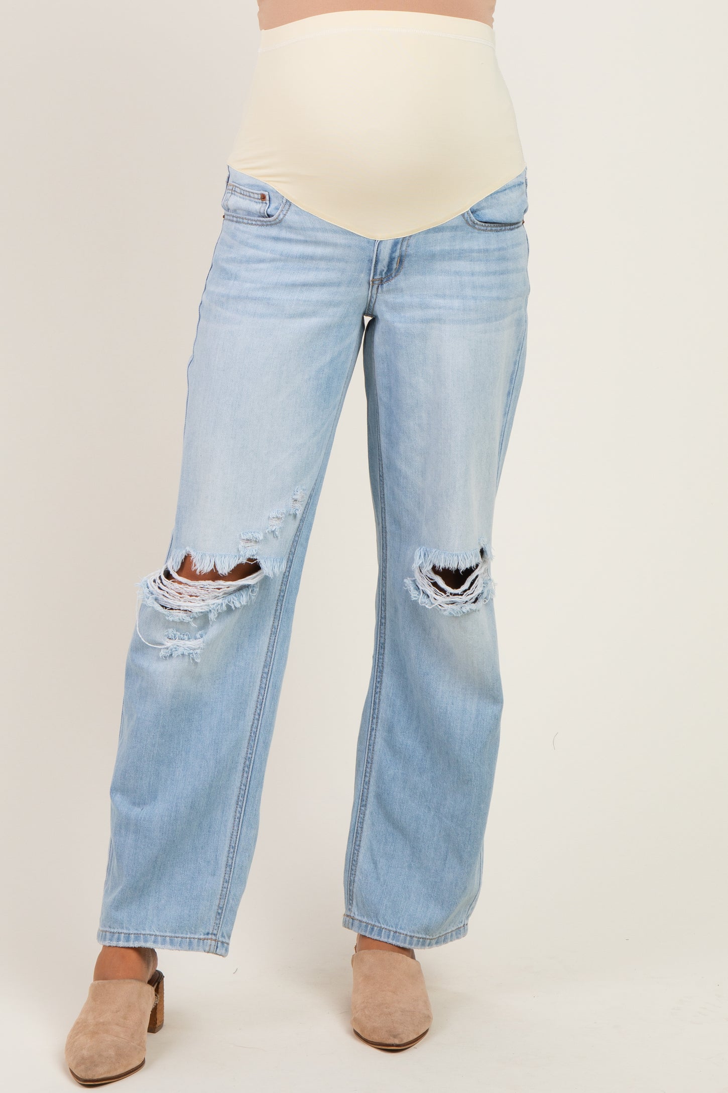 woman wearing light blue distressed maternity jeans with a beige belly panel
