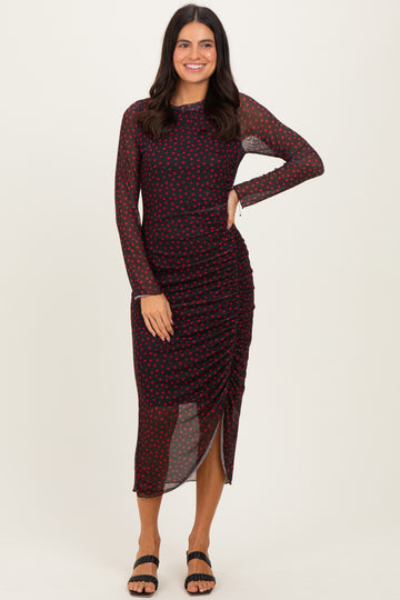 woman wearing a black and red polka dot long sleeve dress with ruching and a side slit