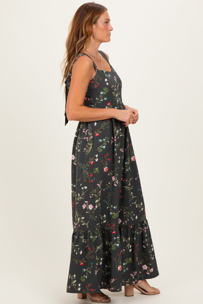 woman wearing a black floral maxi dress with a ruffled hem and tie straps
