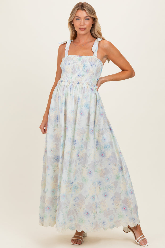 woman wearing a light blue floral maternity maxi dress with smocked bodice and tie straps