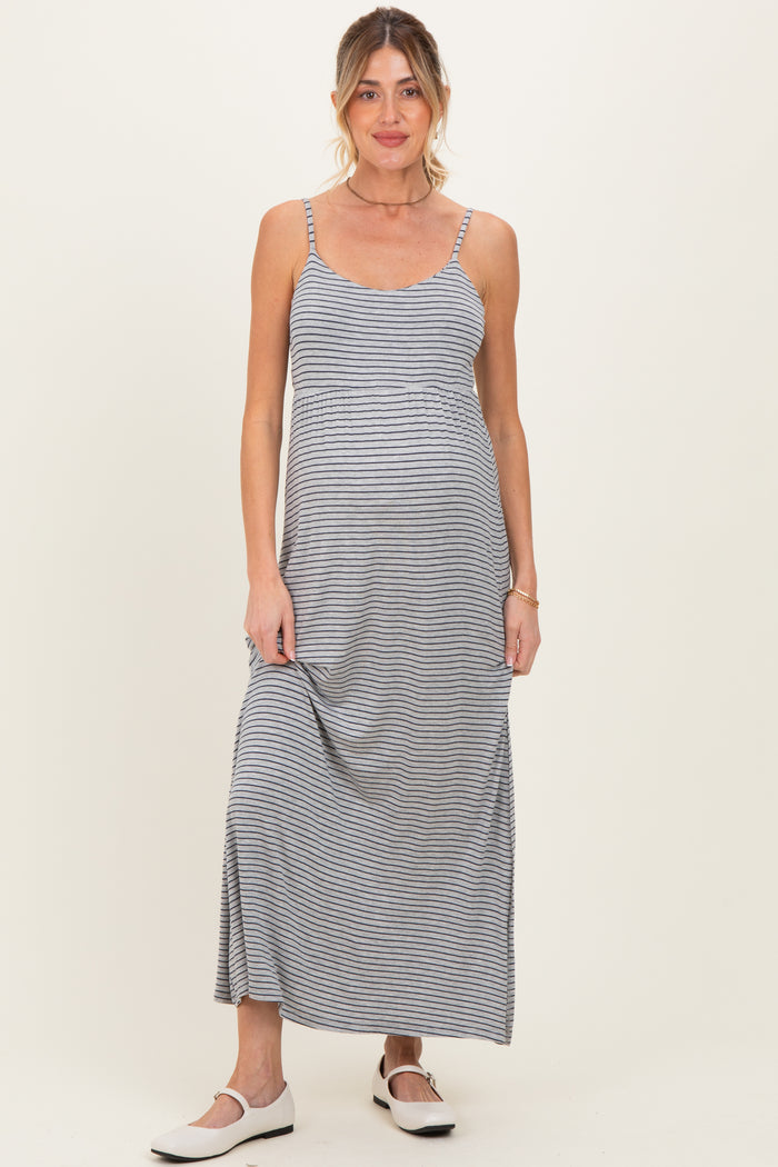 woman wearing a striped gray maternity maxi dress with adjustable straps and a relaxed fit, showing her baby bump