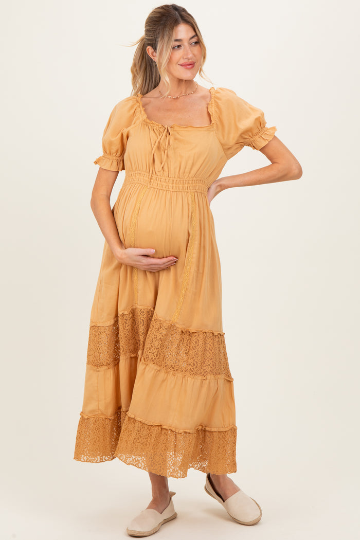 woman wearing a mustard yellow maternity maxi dress with lace details and holding her baby bump