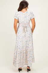 woman wearing a back view of a floral print maternity maxi dress with short sleeves and a tiered skirt