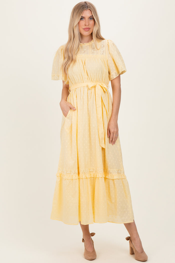 woman wearing a yellow short sleeve midi dress with a tie waist and ruffle hem