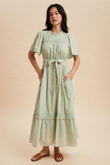 woman wearing a light green maxi dress with short puff sleeves, a cinched waist, and pockets