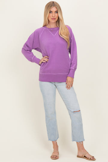 woman wearing a purple oversized sweatshirt paired with light wash distressed jeans and sandals