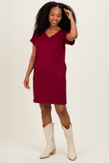 woman wearing a burgundy short sleeve v-neck dress and cream knee-high boots