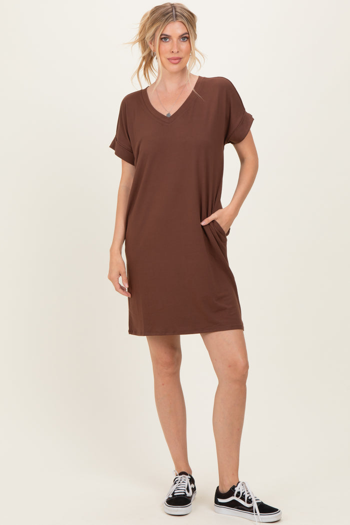 woman wearing a brown short sleeve v-neck dress with pockets and black sneakers
