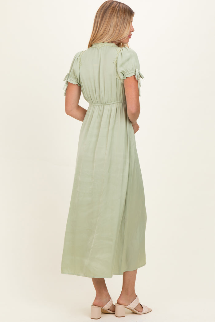 woman wearing a light green maxi dress with short sleeves and tie details at the shoulders, seen from the back