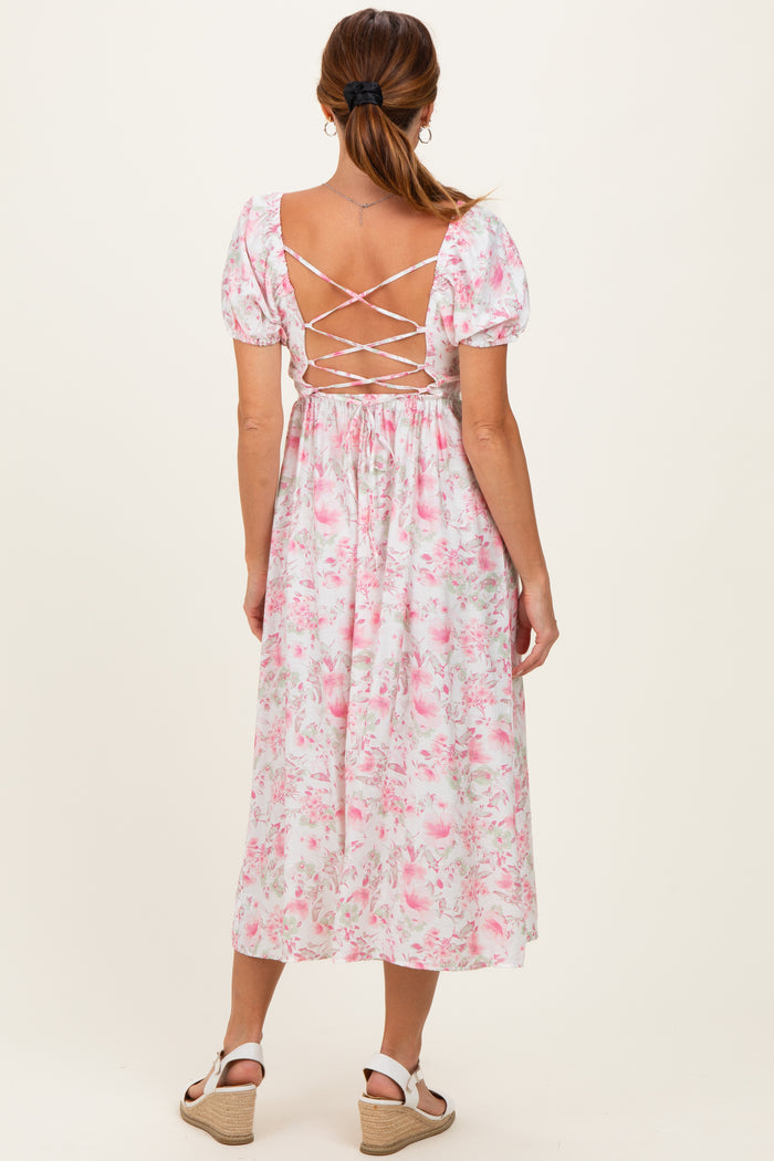 woman wearing a pink floral midi dress with puff sleeves and crisscross back detail