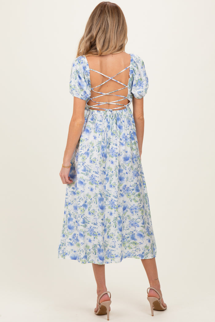 woman wearing a floral backless maternity dress with puff sleeves and lace-up detail, showcasing a baby bump