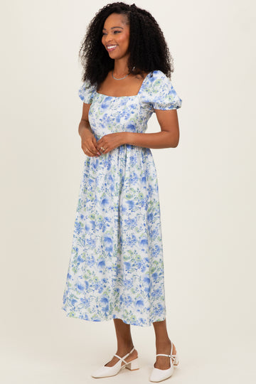woman wearing a floral midi dress with short puff sleeves and a square neckline in blue and green tones