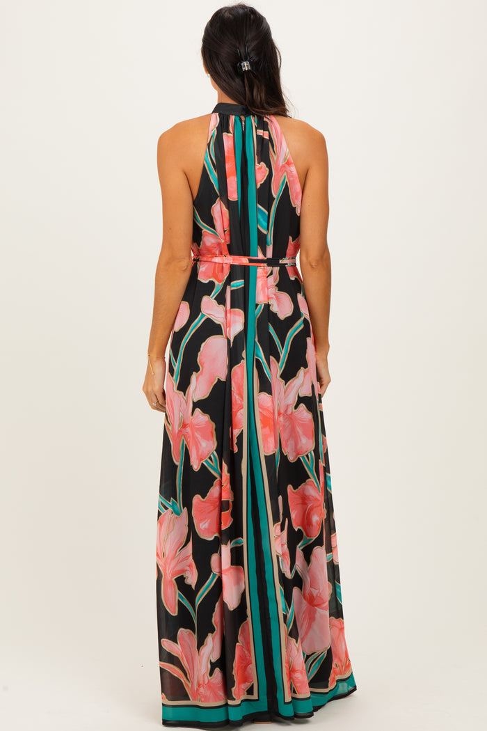 woman wearing a black halter neck maxi dress with a vibrant floral print and contrasting striped details