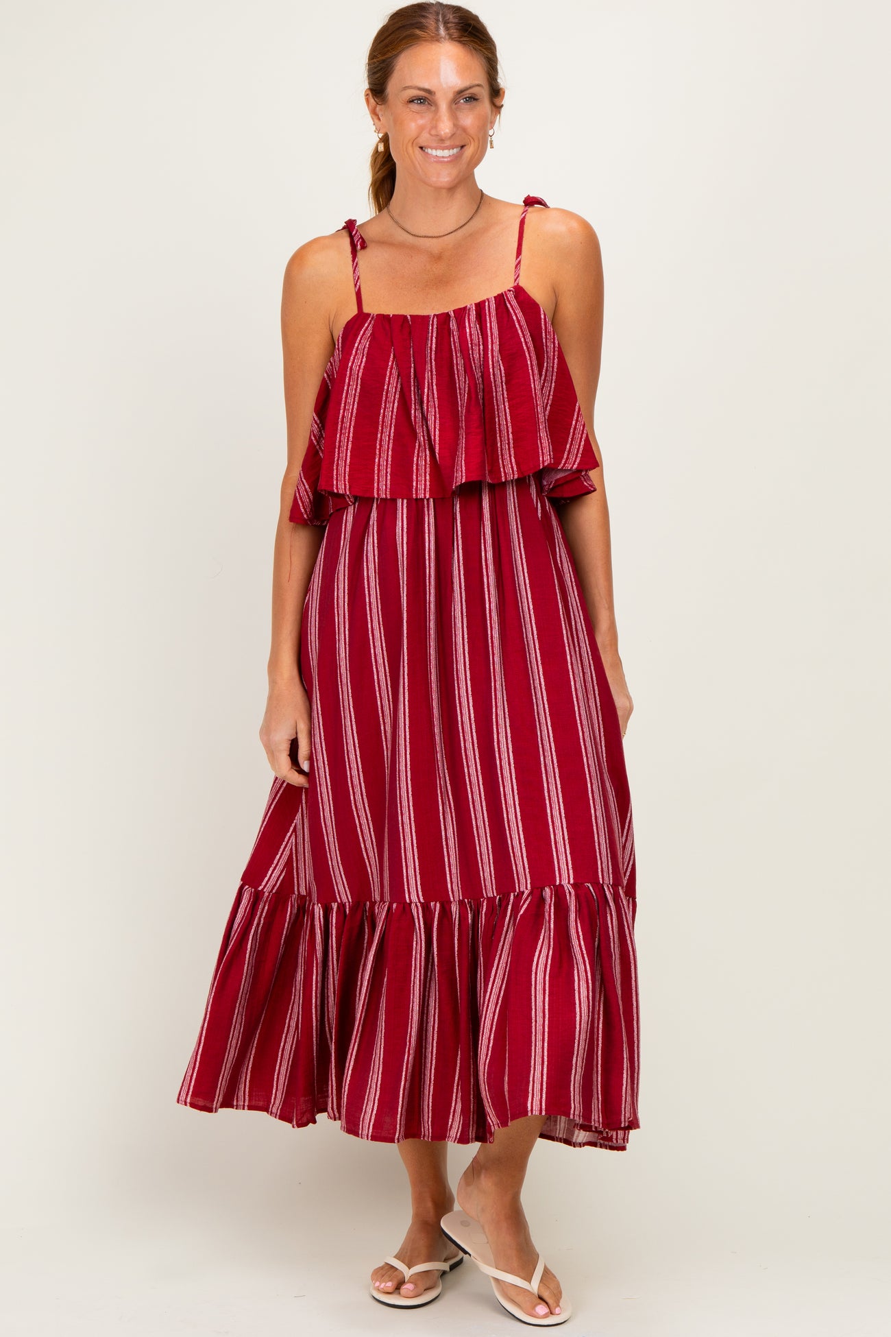 woman wearing a red and white striped maxi dress with ruffled sleeves and a flowing skirt