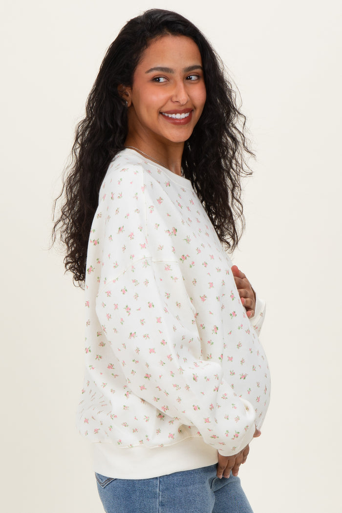woman wearing a cream floral print maternity sweatshirt and showcasing her baby bump