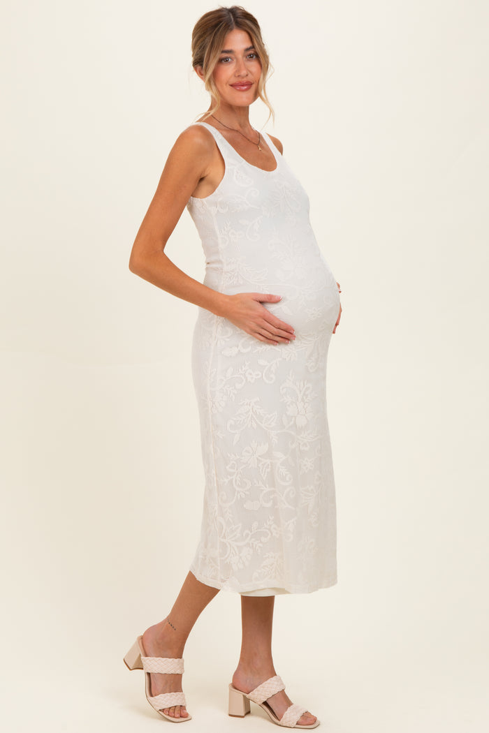 woman wearing a white lace maternity midi dress and gently cradling her baby bump