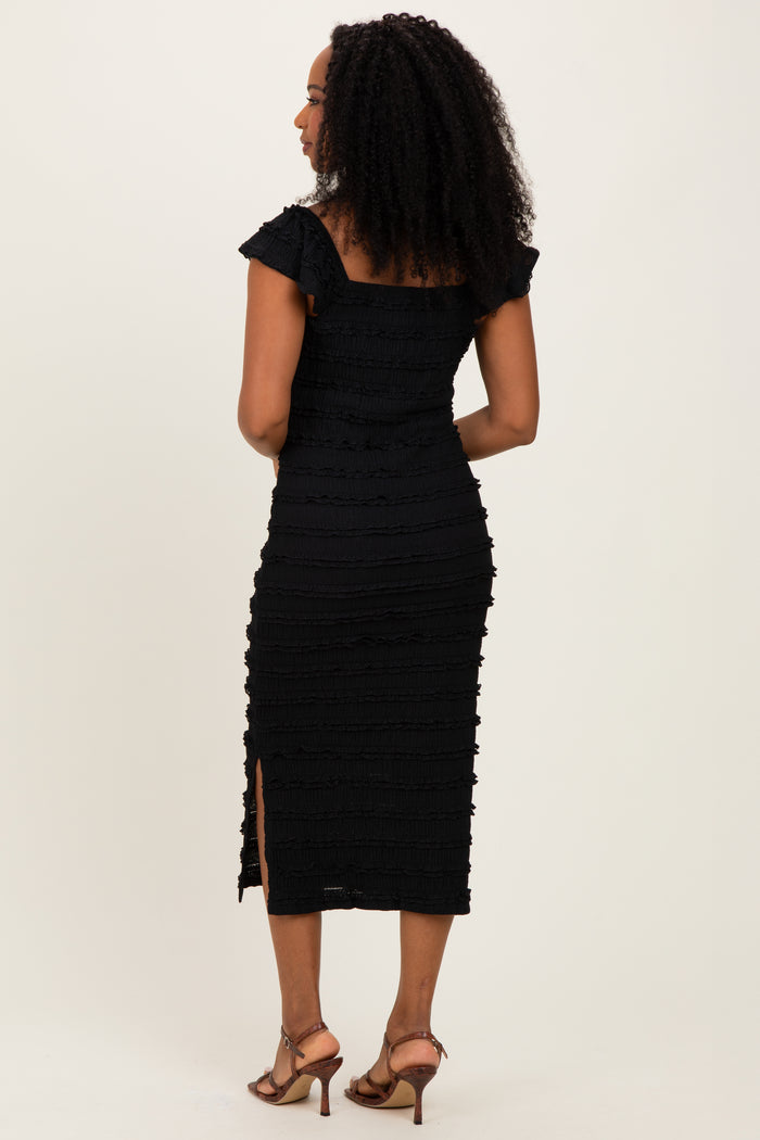 woman wearing a black fitted midi dress with ruffle details and a thigh-high slit, shown from the back