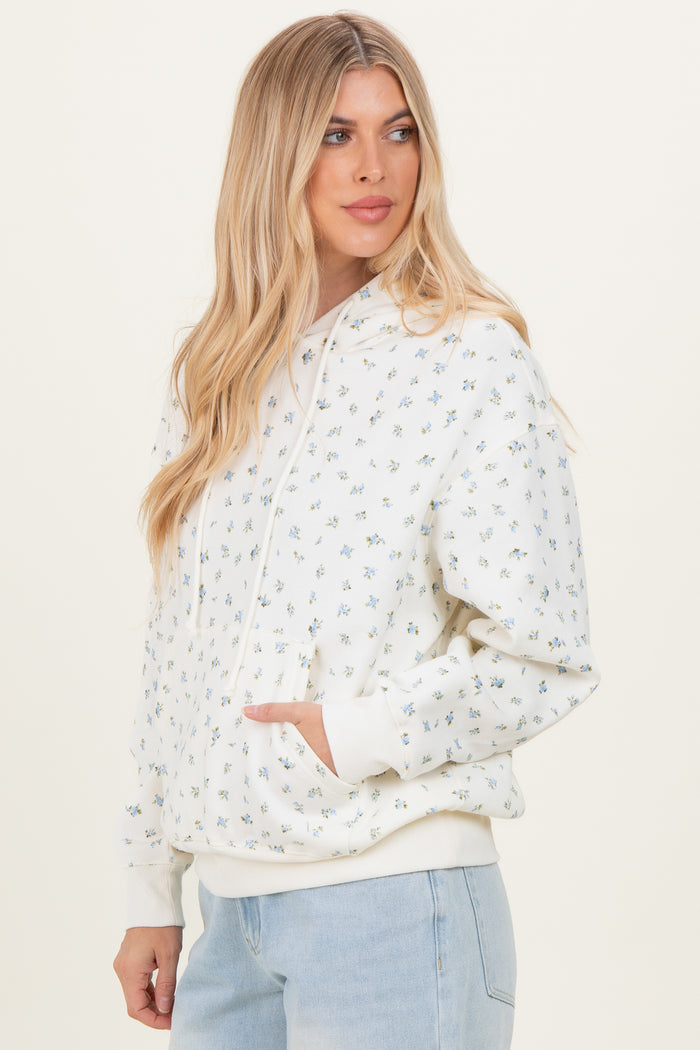 woman wearing a white floral print hoodie with a front pocket and casual fit, styled with light blue jeans