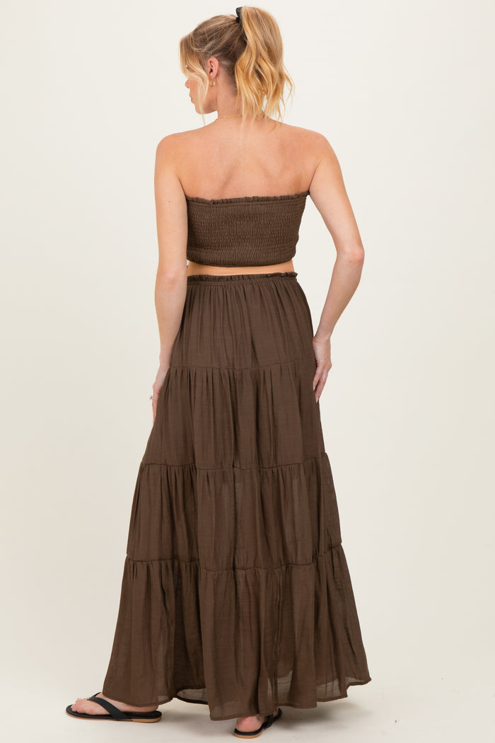 woman wearing a brown strapless maternity dress with a smocked bodice and tiered maxi skirt, showing back view