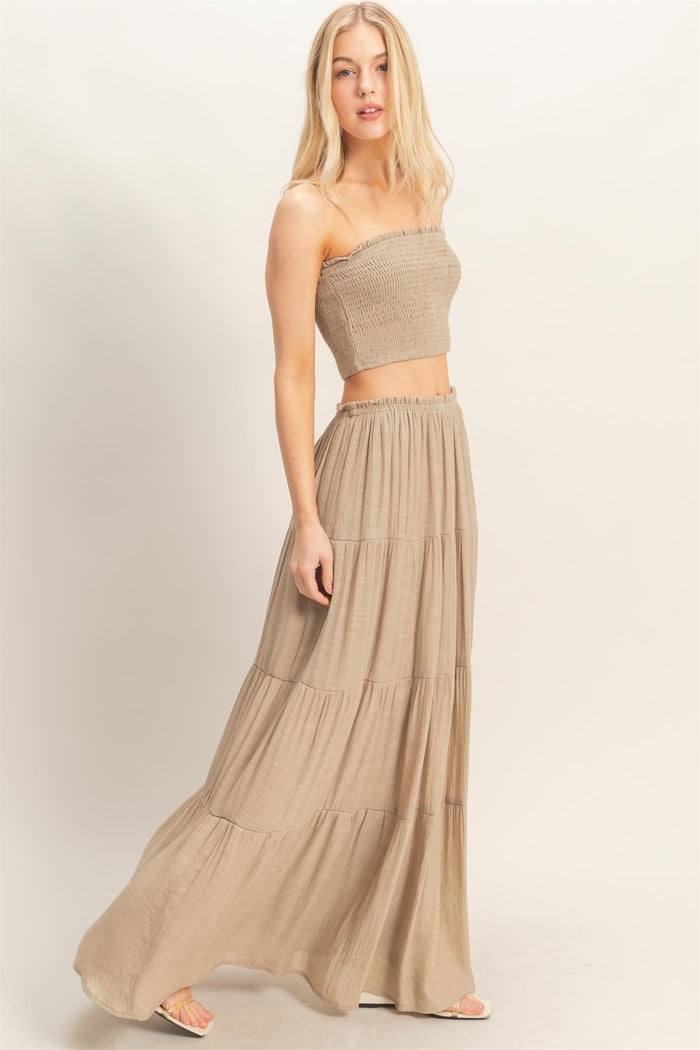 woman wearing a beige strapless crop top and a matching tiered maxi skirt