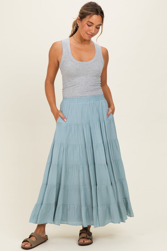 woman wearing a gray tank top and a flowy teal tiered maxi skirt with pockets