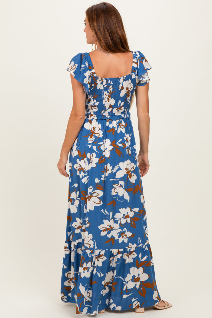 woman wearing a blue floral maxi dress with short flutter sleeves and a smocked bodice, seen from the back