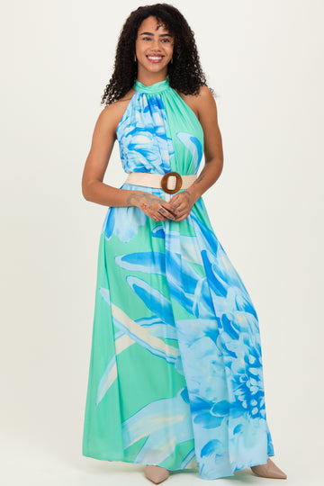 woman wearing a halter neck floral maxi dress in shades of blue and green with a belt at the waist