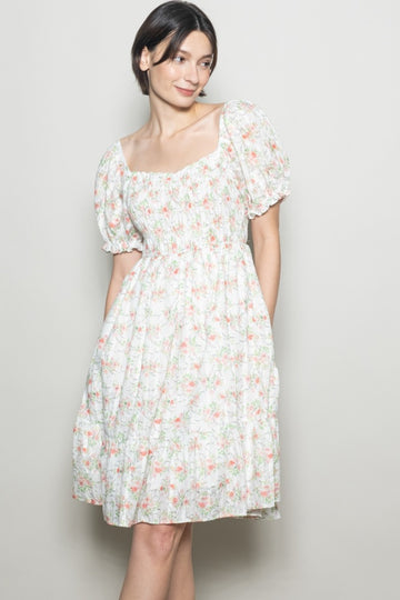 woman wearing a floral short sleeve dress with a square neckline and gathered details
