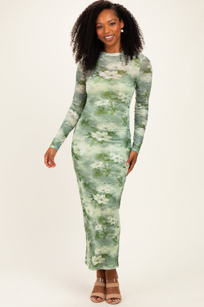 woman wearing a long sleeve green floral maxi dress with a fitted silhouette and a sheer overlay