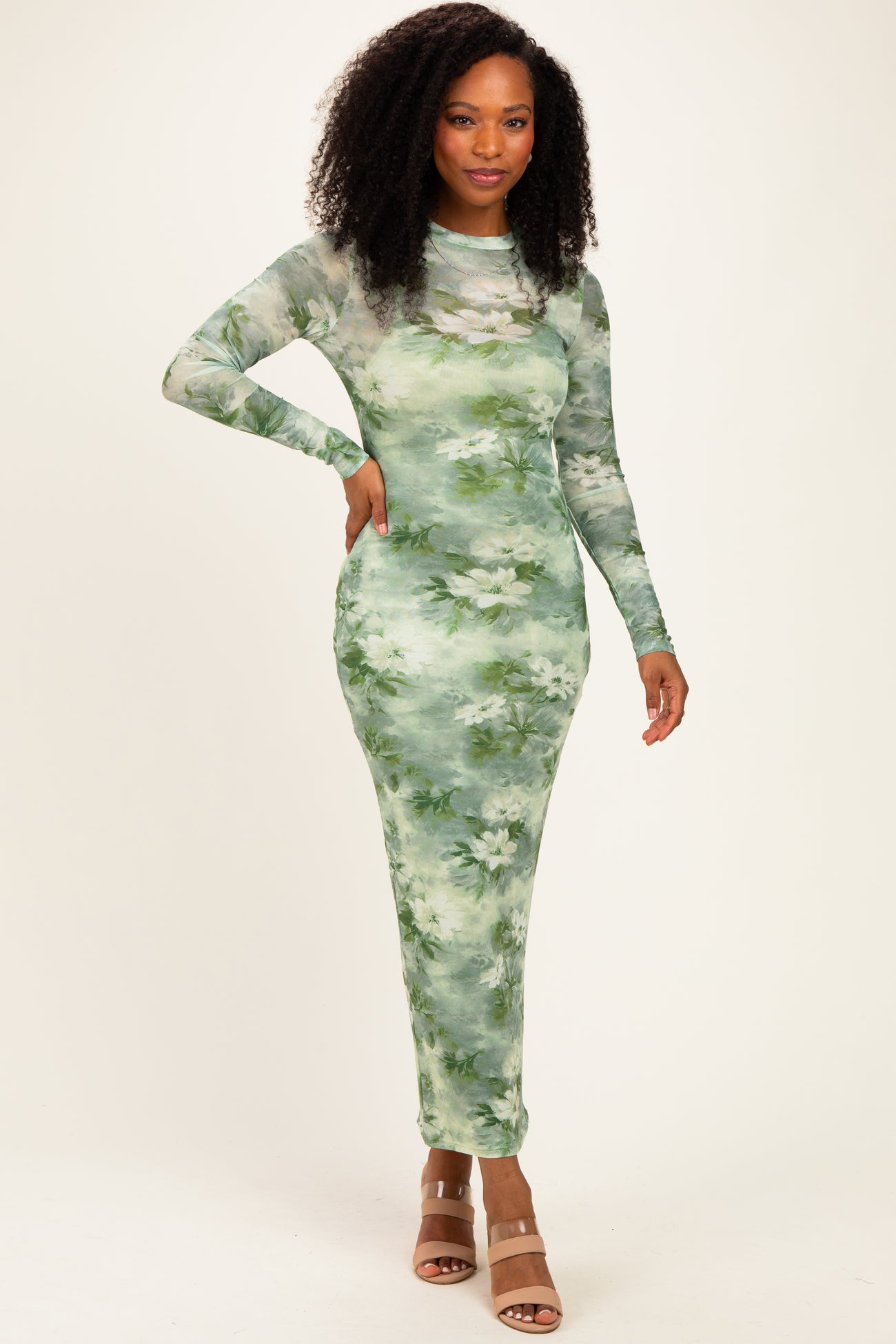 woman wearing a long sleeve green floral maxi dress with a fitted silhouette and side slits