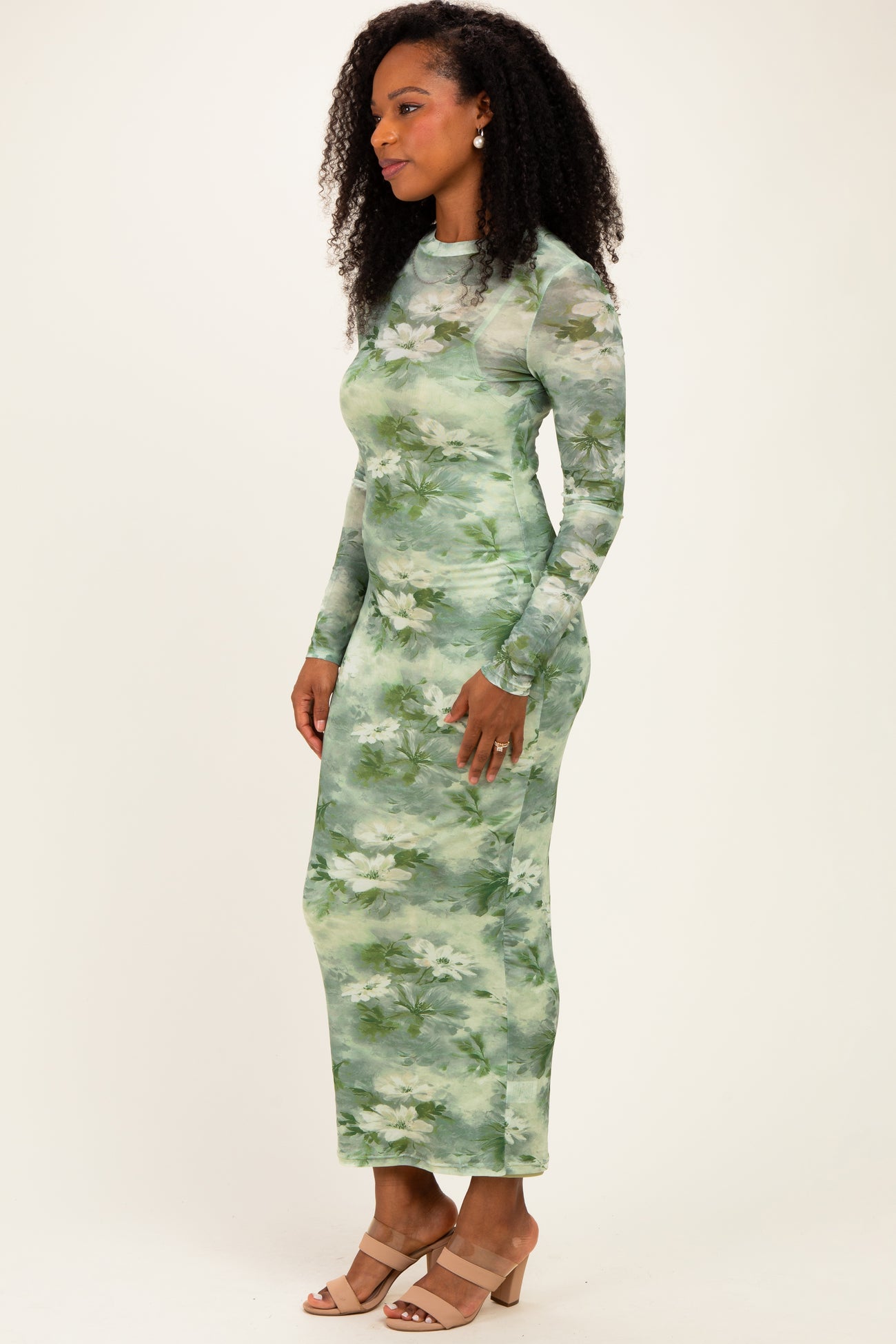 woman wearing a long sleeve green floral maxi dress and beige block heel sandals