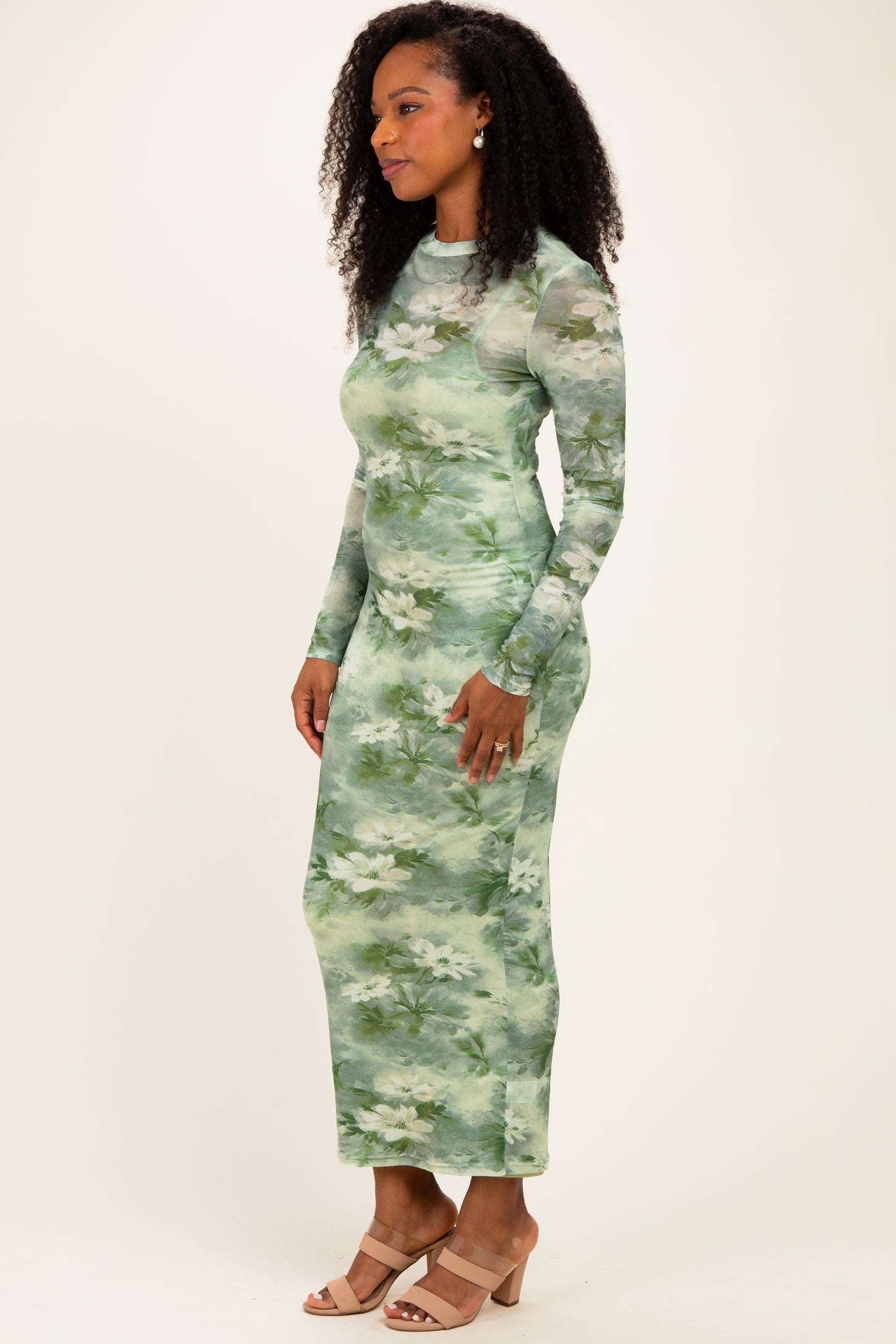 woman wearing a long sleeve green floral maxi dress and beige block heel sandals