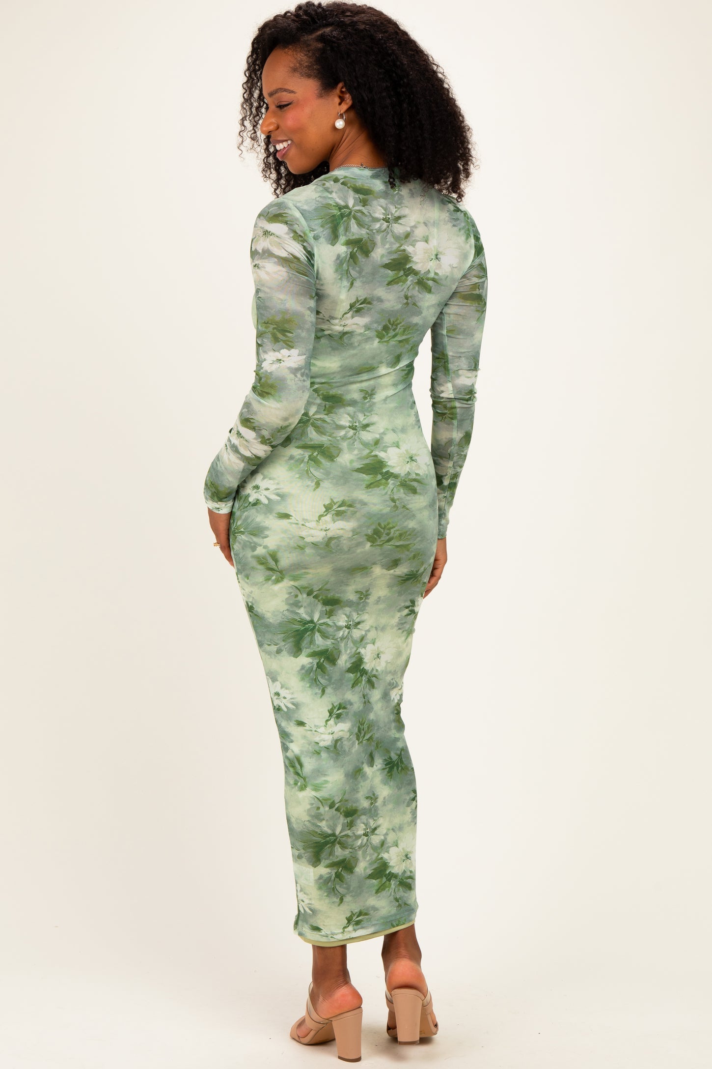 woman wearing a green floral long sleeve bodycon dress, showcasing a fitted silhouette and mid-calf length