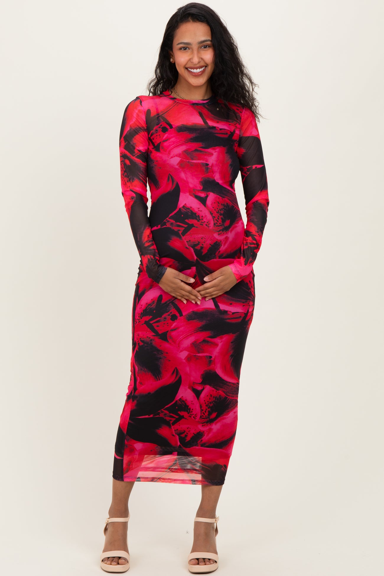 woman wearing a red and black floral long sleeve maternity dress and holding her baby bump