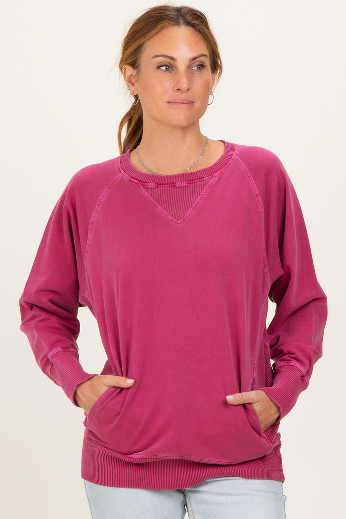 woman wearing a pink oversized sweater with raglan sleeves and side pockets, styled casually with light wash jeans